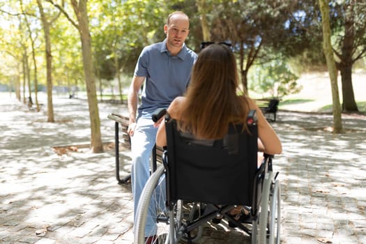 Man and woman having conversation in park, demonstrating care and support for people with disabilities