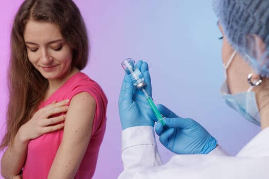 Healthcare professional in blue gloves prepares to administer a vaccine injection to a patient's upper arm using a syringe and vial. concept of modern medicine