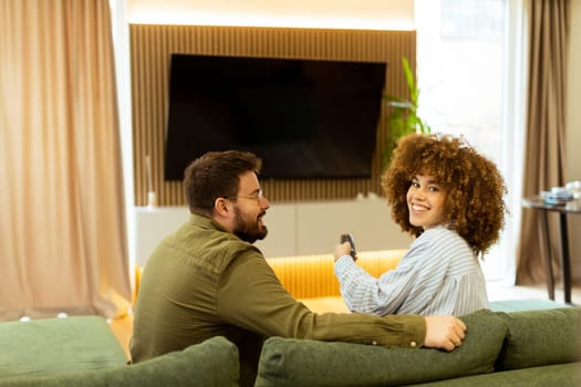 Seated on a comfortable couch, a couple shares a light-hearted moment, laughing and watching their favorite show while surrounded by a warm, inviting atmosphere.
