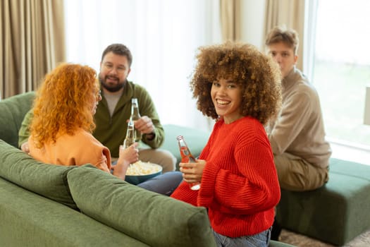 Four friends gather in a cozy living room, sharing laughter and drinks while seated on a comfy sofa. The atmosphere is warm and inviting, perfect for enjoying each other's company.