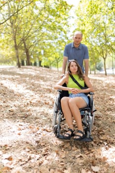 Nurse assisting disabled woman enjoying a sunny day in park