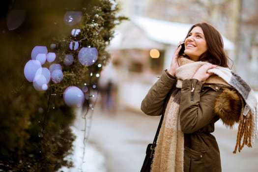 Portrait of smiling young woman with cell phone in winter outdoors