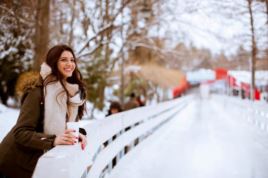 Young woman drinking tea or coffee over winter nature background outdoor