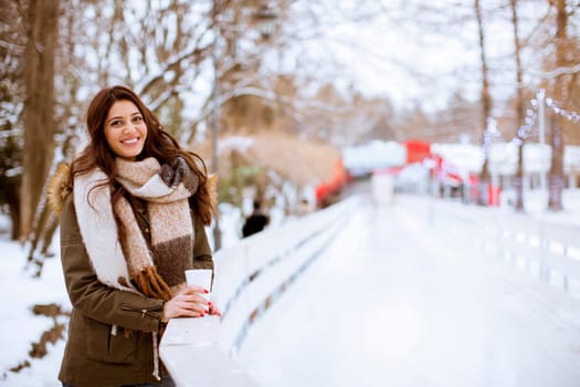 Young woman drinking tea or coffee over winter nature background outdoor