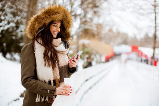 Portrait of young woman in a snow park drinks tea