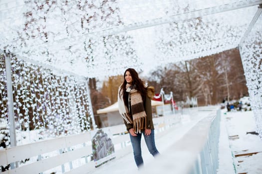 Portrait of young woman rides ice skates in the park on Christmas market