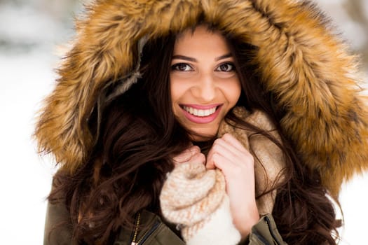 Young woman with a fur hood in the park on the snow