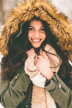 Young woman with a fur hood in the park on the snow