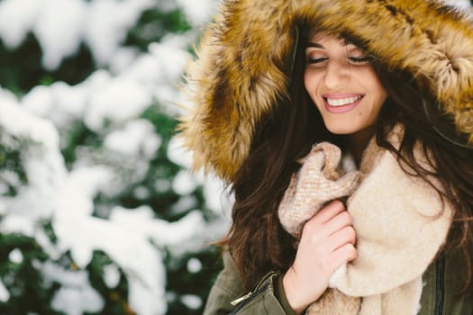 Young woman with a fur hood in the park on the snow