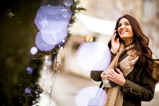 Young woman using a phone in the winter park at Christmas market