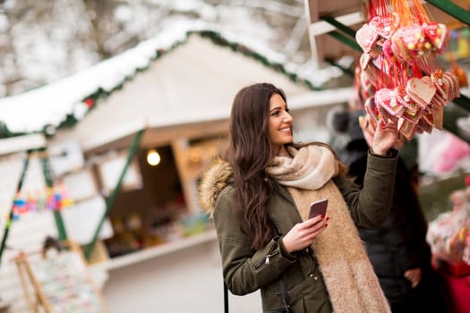 Happy fashion woman using a smart phone on street in winter