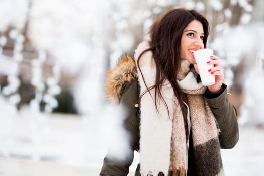 Happy woman with a cup of hot drink on  cold winter outdoors