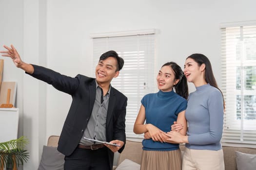 A friendly real estate agent points out key features of a property to two interested clients in a contemporary setting.