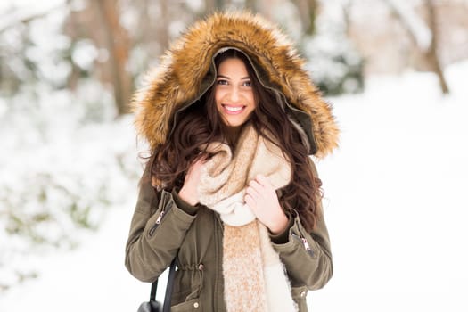 Pretty young woman with hood in the park on the winter day