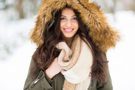 Pretty young woman with hood in the park on the winter day