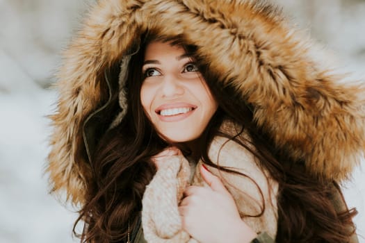Pretty young woman with hood in the park on the winter day