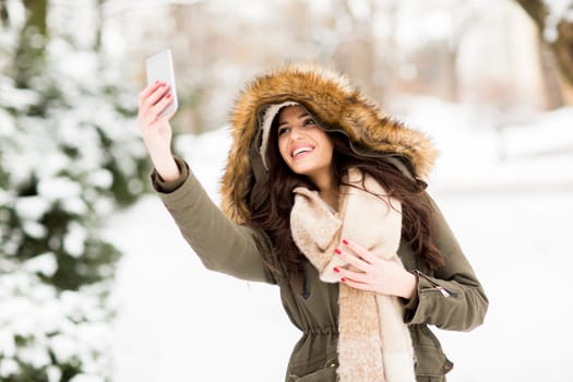 Pretty young woman taking selfie with mobile phone on a cold winter day