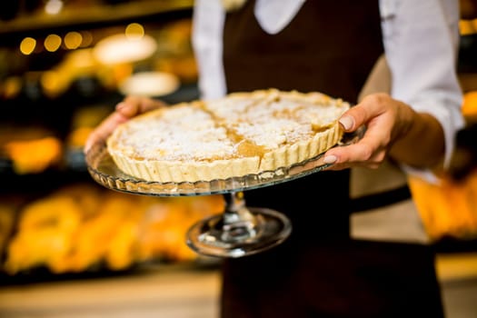 Bakery female worker posing with apple tart in bakery