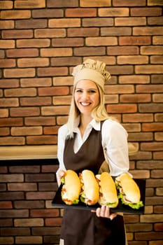 Beautiful female bakery posing with various types of sandwiches in the bakery shop