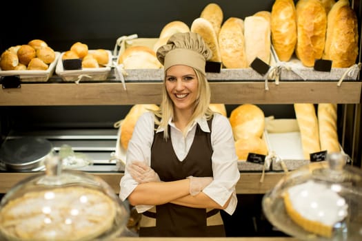 Portrait of friendly female baker with fresh bread smiling in bakery