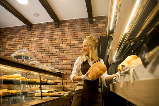 Pretty young woman selling soft  fresh bread in the bakery