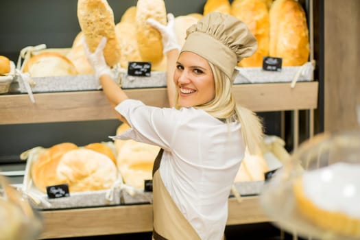 Pretty young woman selling fresh bread in the bakery