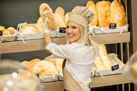 Pretty young woman selling fresh bread in the bakery
