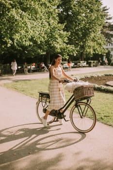 Pretty young woman with white bichon frise dog in the basket of electric bike