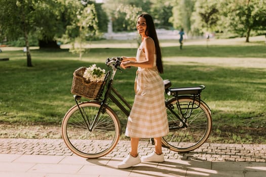 Pretty young woman with flowers in the basket of electric bike