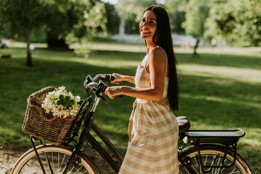 Pretty young woman with electric bike and flowers in the basket