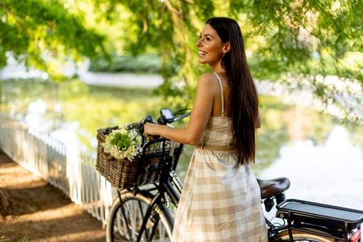 Pretty young woman with flowers in the basket of electric bike