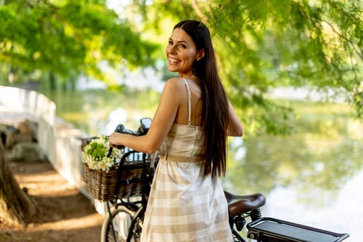 Pretty young woman with flowers in the basket of electric bike