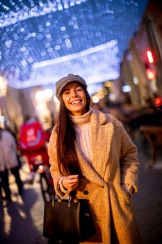 Beautiful young woman on the street at cold Christmas night