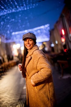 Beautiful young woman on the street at cold Christmas night