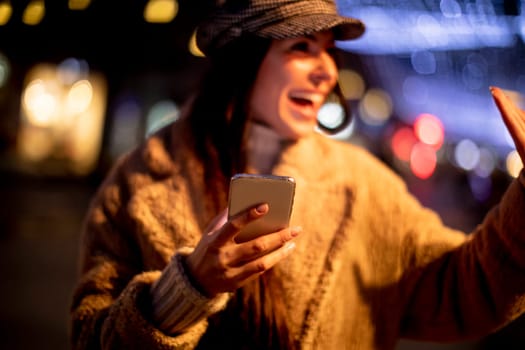 Beautiful young woman using her mobile phone in the street at Christmas time
