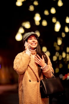 Beautiful young woman using her mobile phone in the street at Christmas time
