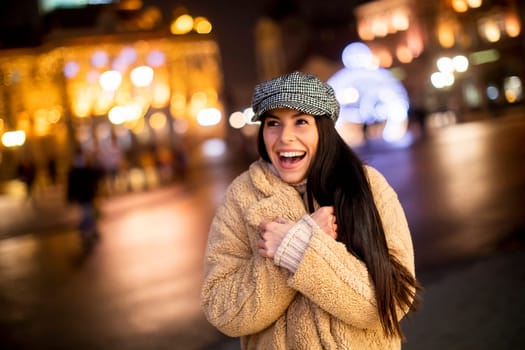 Beautiful young woman on the street at cold Christmas night