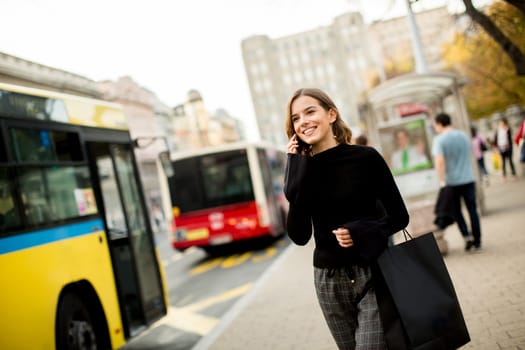 Portrait of young woman waiting for taxi or bus on the street in the city