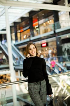 Young woman standing in shopping mall talking over mobile phone