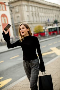 Portrait of young woman waiting for taxi or bus on the street in the city