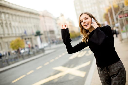 Young woman waiting for taxi or bus on the street in the city