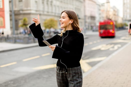 Young woman waiting for taxi or bus on the street in the city