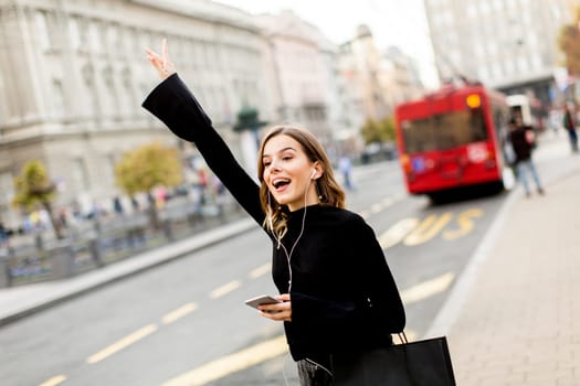 Portrait of young woman waiting for taxi or bus on the street in the city