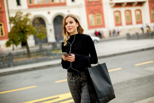 Young woman waiting for taxi or bus on the street in the city