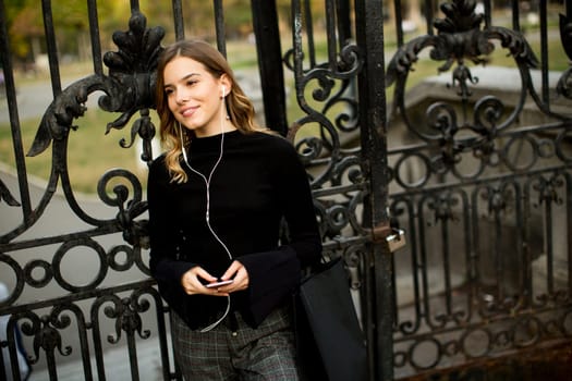 Portrait of modern young shopaholic woman by fence