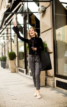Young woman on the street with mobile phone and listening music