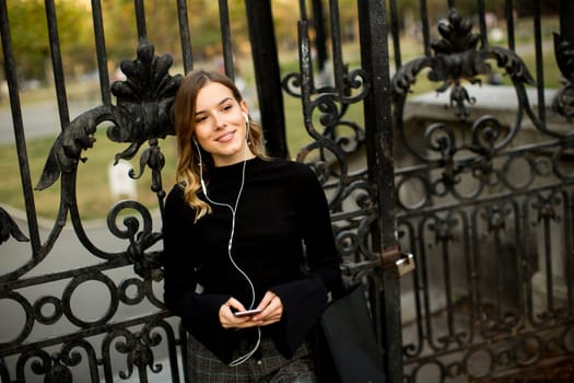 Portrait of modern young shopaholic woman by fence