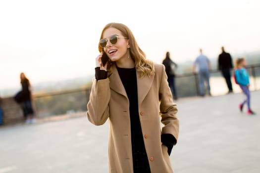 Portrait of young woman with eyeglasses with mobile phone outdoor