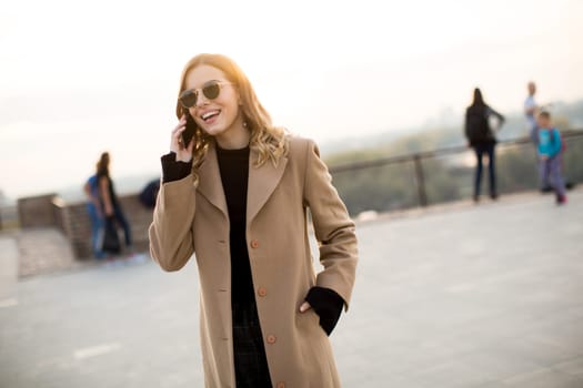 Portrait of young woman with eyeglasses with mobile phone outdoor