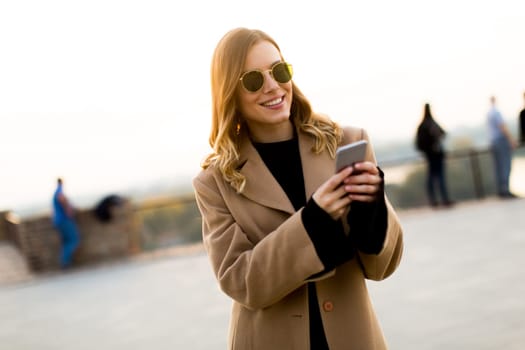 View at modern woman using mobile phone at autumn outdoor